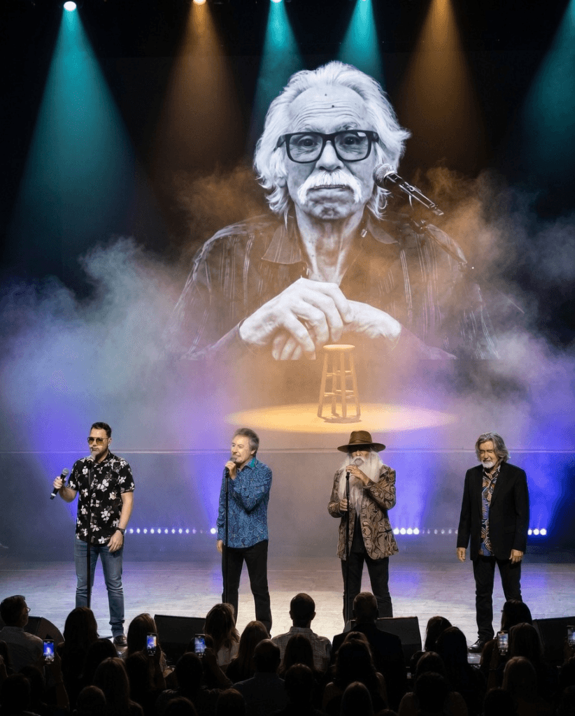 A RARE DISEASE TOOK HIS LEGS AFTER 50 YEARS. BUT HIS BROTHERS MADE SURE HE NEVER LEFT THE ROAD. Joe Bonsall’s tenor fueled 41 million records for The Oak Ridge Boys. When a neuromuscular disorder stole his mobility, he spent years performing on a stool, insisting: “I can’t walk, but I can still sing.” Forced to step away in early 2024, his bandmates didn’t just move on. They carried his memorabilia on every tour bus—treating it like a silent fifth member. On July 9, 2024, Joe died at 76. Most bands replace a singer instantly. They held his space. The story behind their very first concert without him—and the unseen tribute placed exactly where he used to sit—remains one of the quietest, most powerful mysteries in country music history. 1 image 478